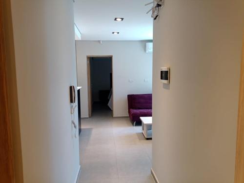 pasillo que conduce a una sala de estar con sofá púrpura en Depto Nuevo Belgrano en Villa Mercedes