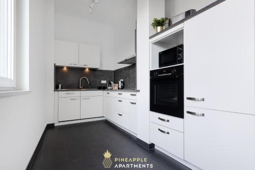 a white kitchen with white cabinets and black appliances at Pineapple Apartments Penthouse am Zwinger - 162 qm - 1x free parking in Dresden
