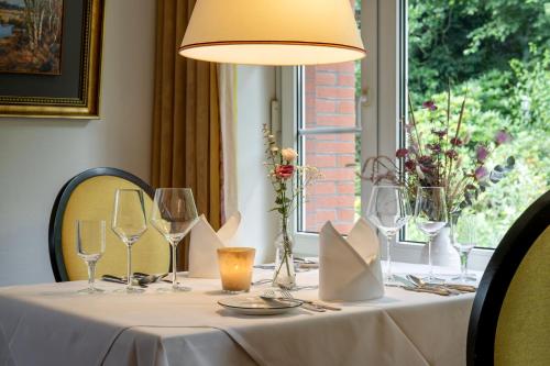 a table with a white table cloth and wine glasses at Köhlers Forsthaus Wellness & Genuss Hotel in Aurich