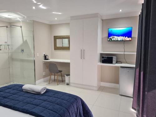 a bedroom with a blue bed and a tv on the wall at Cape Winelands Business Villas in Joostenberg Vlakte