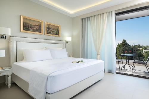 a white bedroom with a large bed and a balcony at Light Blue Hotel in Nea Kalikratia