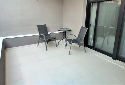 two chairs and a table in a room with windows at Light Blue Hotel in Nea Kalikratia