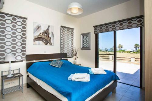 een slaapkamer met een blauw bed en een groot raam bij Villa Lara Latchi in Lachi