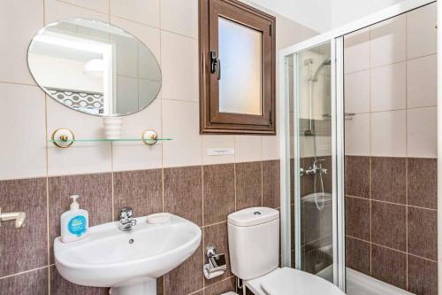 een badkamer met een wastafel, een toilet en een spiegel bij Villa Lara Latchi in Lachi