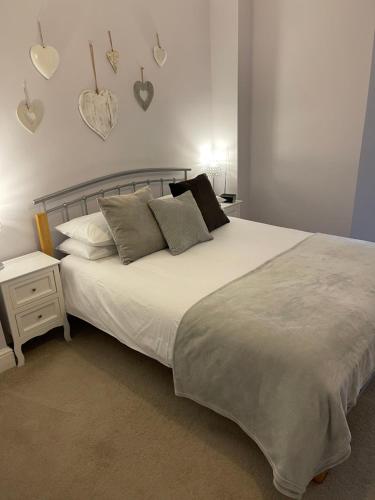 a bedroom with a white bed with hearts on the wall at Nythfa Guest House in Saundersfoot