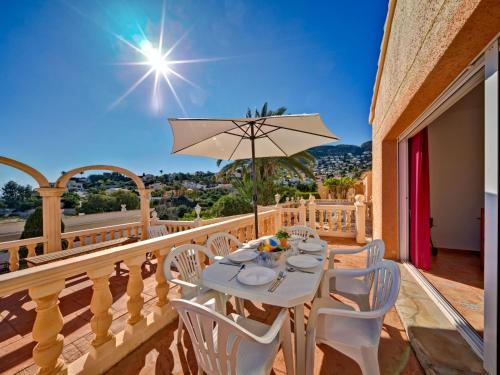 un tavolo con sedie e un ombrellone su un balcone di Apartment Canuta Baja-8 by Interhome a La Canuta