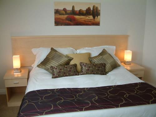 a bedroom with a bed with pillows and two lamps at Springfields in Horsham