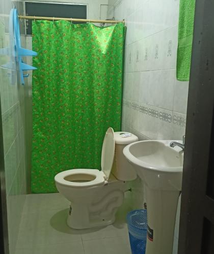 baño con aseo y cortina de ducha verde en HOTEL PRIMAVERA, en Guayaquil