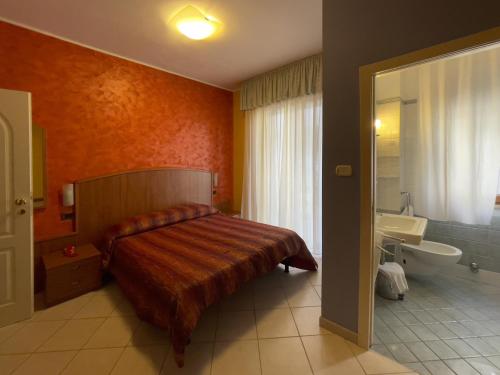een slaapkamer met een bed en een badkamer met een wastafel bij La Lanterna in Silvi Marina