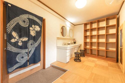 宿坊 志摩房 - Temple Hotel Simanobo في Minobu: غرفة مع باب مع حوض ومكتب