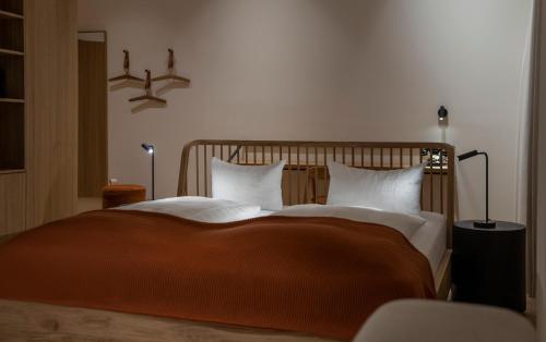 a bedroom with a large bed with orange blanket and white pillows at Posthotel Lechtal, Arlberg in Holzgau