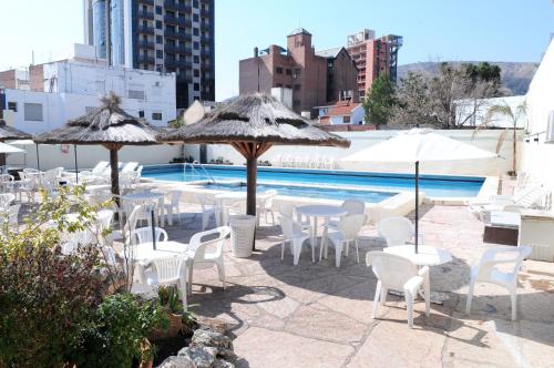 a group of tables and chairs with umbrellas and a pool at Hotel Presidente in Villa Carlos Paz