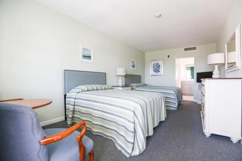 1 dormitorio con 2 camas, mesa y silla en The Heritage Inn, en Cape May