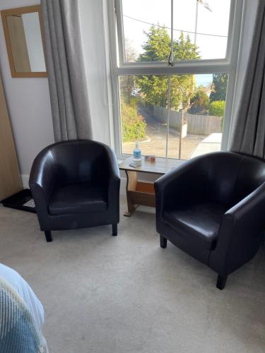 two black chairs sitting in a room with a window at Nythfa Guest House in Saundersfoot