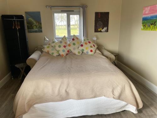 a bedroom with a bed with pillows and a window at Pool House, farm stay in Brackley