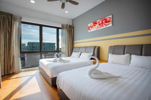 a hotel room with two beds with a swan on them at AJ Suites @ Loft Imago KK in Kota Kinabalu