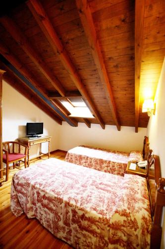 a bedroom with a large bed and a wooden ceiling at Puente Romano in Cangas de Onís