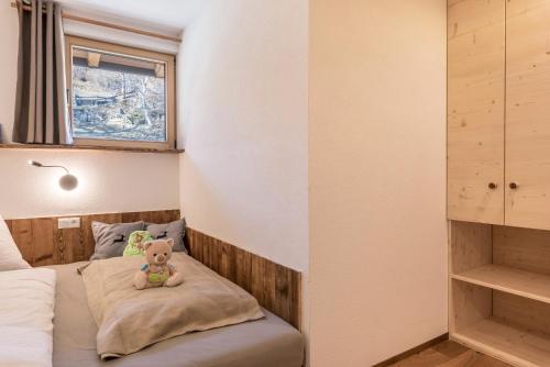 una piccola camera da letto con un orsacchiotto seduto su un cuscino di Aschnerhof Holzhitt a Collalbo