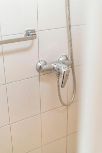 a shower in a bathroom with white tiles at Elckerlyck Inn Hotel in Rollegem