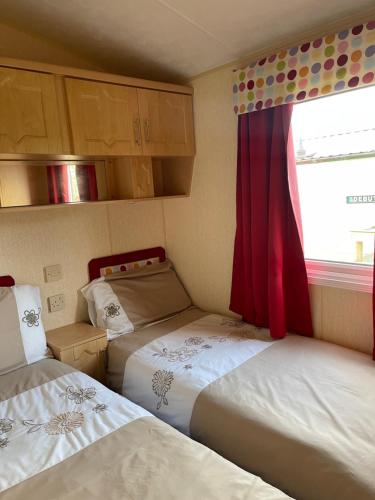 a small room with two beds and a window at Immaculate 2-Bed Static Caravan at Monrieth in Newton Stewart