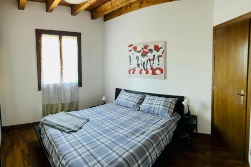 1 dormitorio con 1 cama con manta de cuadros azul en Casa Sunta, en Tarzo