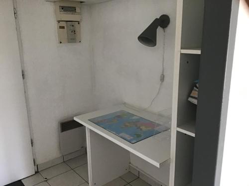een wit bureau met een lamp en een plank bij Studio quartier Porcé 5 mn plage in Saint-Nazaire