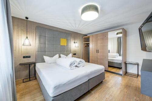 a bedroom with a large white bed and a mirror at Appartements Perberschlager in Oetz