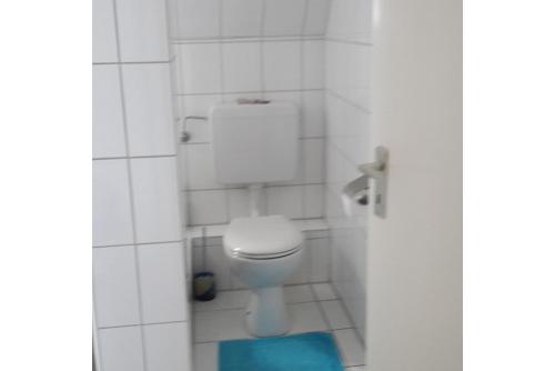 a bathroom with a white toilet and a blue rug at Private Room in Hannover