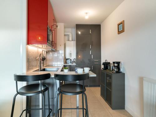 una cocina con 2 taburetes y una cocina con armarios rojos en Apartment Xabadenia-4 by Interhome, en Bidart