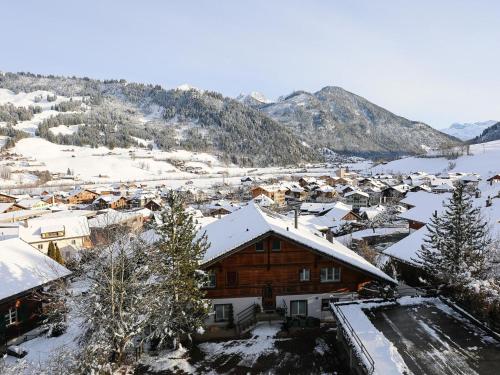 un village recouvert de neige avec des montagnes en arrière-plan dans l'établissement Apartment Sparenmoos - OB - DG Süd-West by Interhome, à Zweisimmen