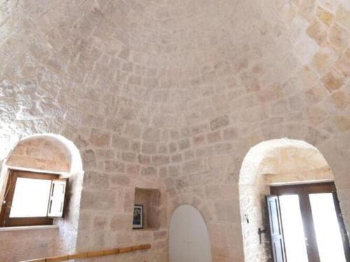 Cette chambre dispose de deux fenêtres et d'un mur en pierre. dans l'établissement Trulli holiday home with private pool near Ostuni, à Ostuni