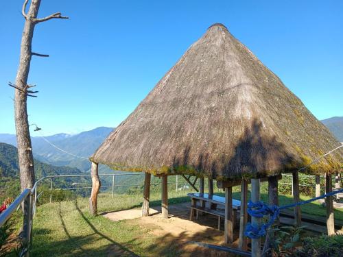 a hut with a bench and a grass roof at Hiwang Native House Inn & Viewdeck in Banaue