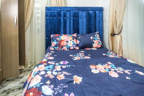 Bett mit blauem Kopfteil und Blumen drauf in der Unterkunft Adorable 1-Bedroom-Apt With 24hrs Electricity & Unlimited Internet in Lagos