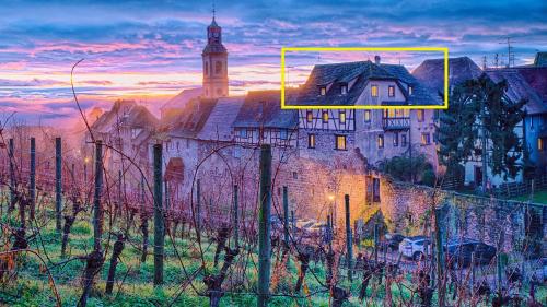 een oud kasteel met een klokkentoren en een gebouw bij Remparts de Riquewihr - La Cigogne Blanche in Riquewihr