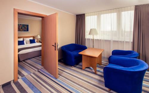 a hotel room with blue chairs and a bed at Hotel Mercure Toruń Centrum in Toruń