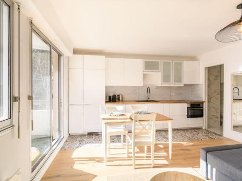 une cuisine avec des armoires blanches et une table et des chaises dans l'établissement Apartment Feodorowka-2 by Interhome, à Arcachon