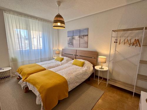 una camera da letto con un grande letto con una coperta gialla di Villa Yoli, céntrico con plaza de garaje ad Avilés