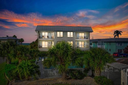 a house with palm trees in front of a sunset at Absolute Anna Maria-Private Beach Access-Heated Pool-Water Views From Every Room in Bradenton Beach