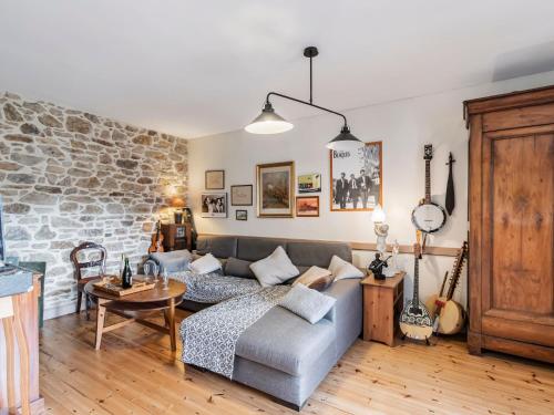 un salon avec un canapé et un mur en pierre dans l'établissement Holiday Home Les Roses by Interhome, à Yffiniac