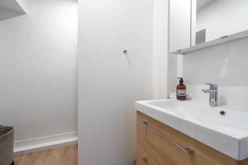 une salle de bain avec un lavabo blanc et un miroir dans l'établissement Le Puits d'Argent - Spacieux T2 au Coeur de Nantes, à Nantes