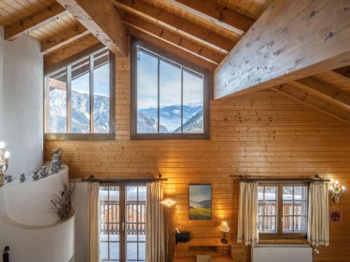 a room with wooden walls and windows and mountains at Chalet Le Sorbier by Interhome in Chamoson
