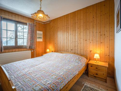 a bedroom with a bed with wooden walls and a window at Chalet Le Sorbier by Interhome in Chamoson
