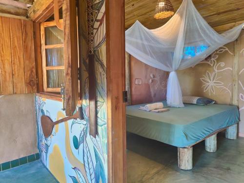 a bedroom with a bed with a mosquito net at Casa de Terra in Caraíva