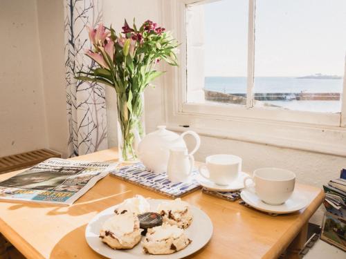 uma mesa com dois pratos de comida e um vaso com flores em Holiday Home Cliff Cottage by Interhome em Mevagissey