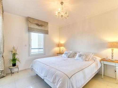 - une chambre avec un grand lit blanc et un lustre dans l'établissement Apartment Le 4 Mats-2 by Interhome, à Fréjus