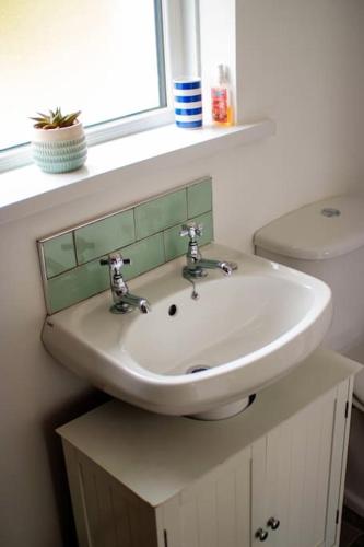 a bathroom with a sink and a toilet at Mary Jane's Cottage, Lettermacaward in Doochary