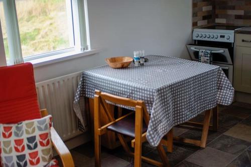 a kitchen with a table with a black and white table cloth at Mary Jane's Cottage, Lettermacaward in Doochary