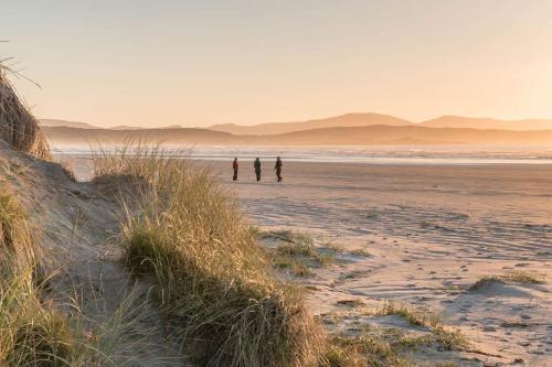 two people standing on a beach near the ocean at Mary Jane's Cottage, Lettermacaward in Doochary