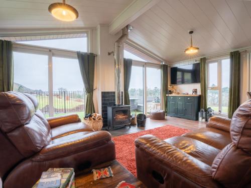 sala de estar con sofá de cuero y chimenea en Chalet Loch Leven Lodge 25 East by Interhome, en Kinross