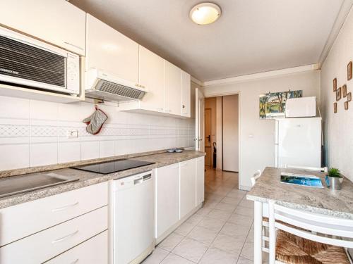 une cuisine avec des armoires blanches et un réfrigérateur blanc dans l'établissement Apartment Le Consul-2 by Interhome, à Fréjus